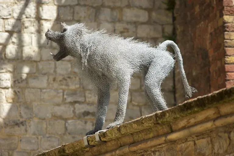 Escultura de filferro d’un babuí encimbellat en un mur, part de l’exposició Royal Beasts a la Tower of London