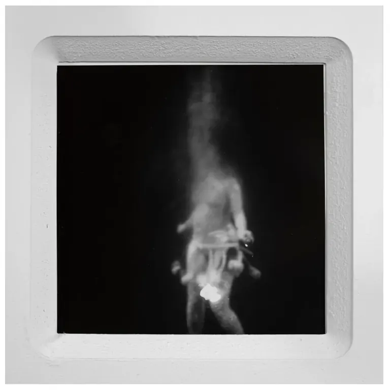 Black-and-white photograph of a blurred figure in a recessed white frame, from Sideways Glance