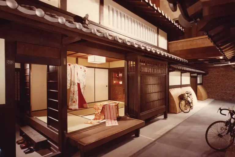 Interior of the Japanese House at Boston Children's Museum, a two-storey wooden Kyoto townhouse with tatami rooms, a hanging kimono and a bicycle in the street outside