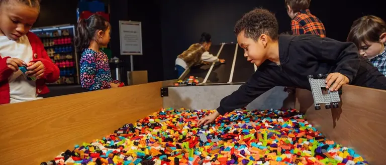 أطفال يبنون على منحدر من قطع LEGO في مساحة اللعب