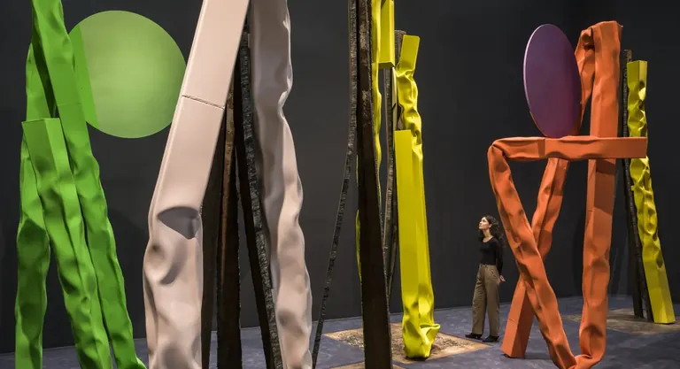 Brightly colored steel sculptures by Carol Bove in the Guggenheim's gallery, with a visitor looking up at the forms