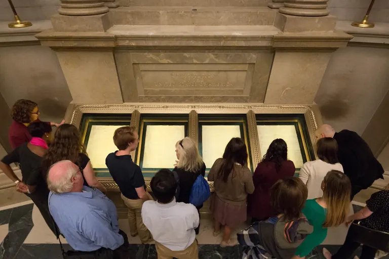 Visitors gathered around the encased original US Constitution in the National Archives Rotunda