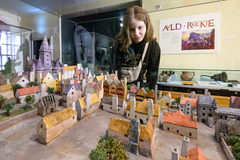 Une femme observe une maquette de la vieille ville médiévale d’Édimbourg, avec ses bâtiments et ses ruelles finement représentés