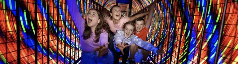 Des visiteurs dans le labyrinthe de miroirs et le tunnel à vortex de l’étage Bewilderworld