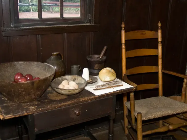 The restored kitchen inside the Paul Revere House, with a large open hearth and period cooking implements