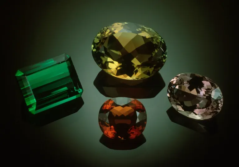 Four coloured gems - green, yellow, red and pink - on a black background