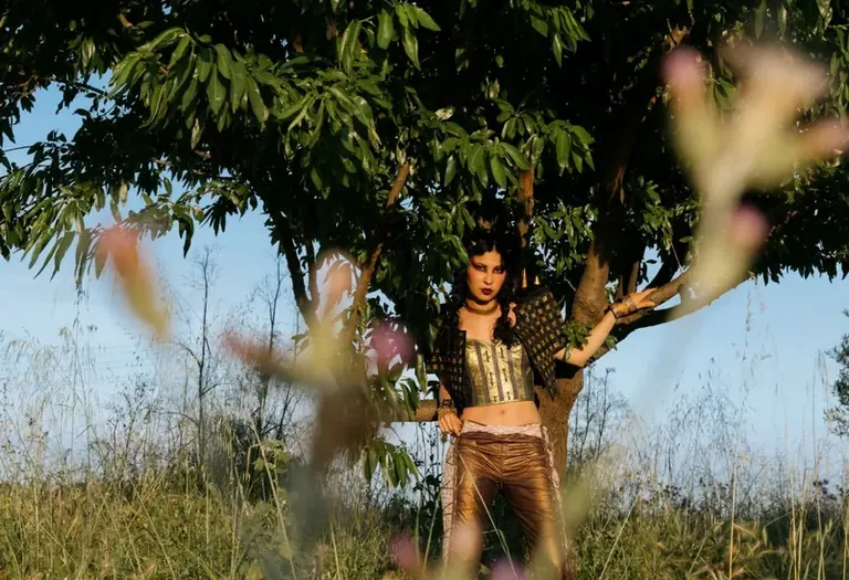 Model in a studded vest and metallic trousers under a tree, image for Mater is the ultimate punk