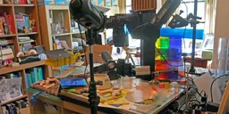 Martin Venezky's studio, with a camera rig and lights over a table of coloured paper, acrylic blocks and glassware