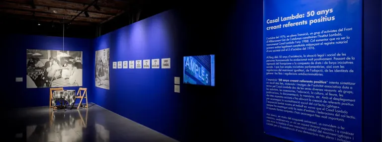 Blue gallery walls with archive photographs and the introduction panel of Casal Lambda. 50 anys creant referents positius