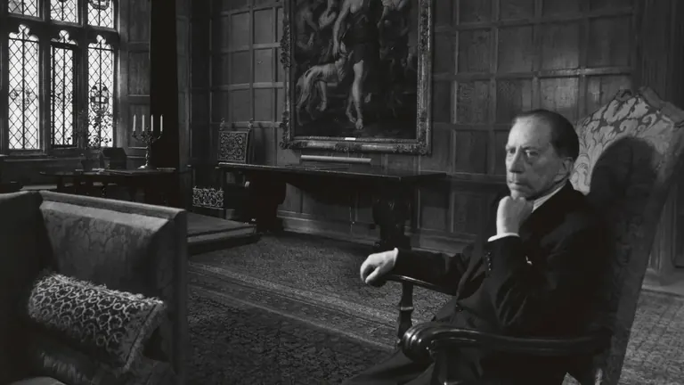1964年黑白照片：J. Paul Getty 坐在英格兰 Sutton Place 一间装饰华丽、铺设木护墙板的房间里