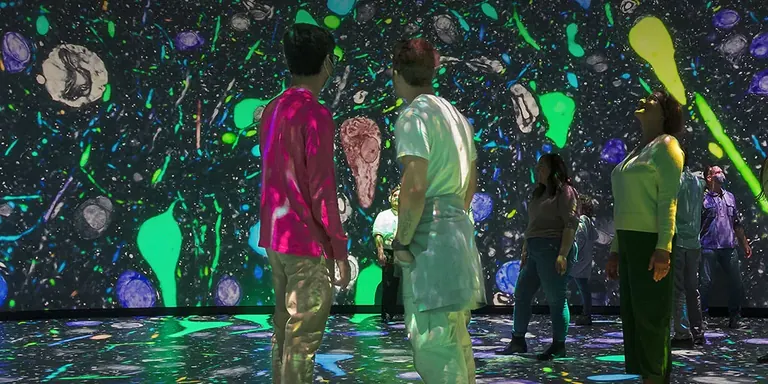 Besucher stehen im immersiven Theater Invisible Worlds und sind von Projektionen umgeben