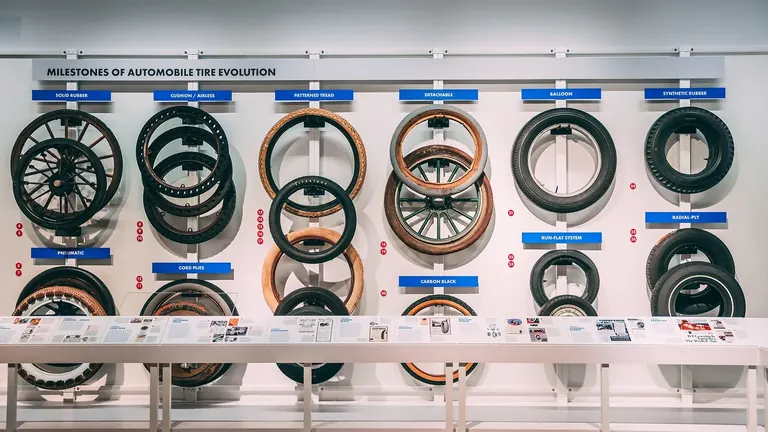 Mur de pneus historiques disposés sous le titre « Milestones of Automobile Tire Evolution »