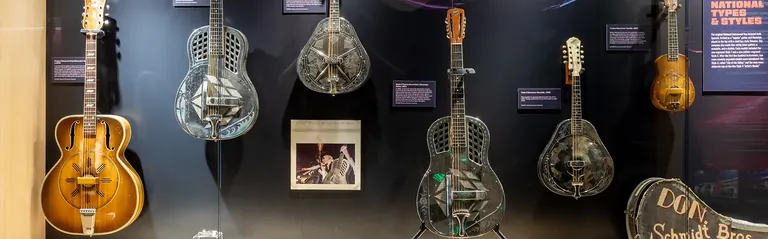 Vitrina amb guitarres ressonadores i mandolines National d’època, i una portada d’un àlbum de Johnny Winter