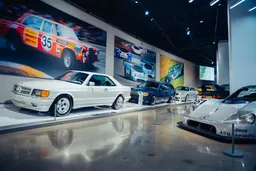 Rangée de Mercedes-Benz dans la galerie, en tête une 500 SEC AMG blanche, avec au premier plan une voiture de course Sauber-Mercedes argentée
