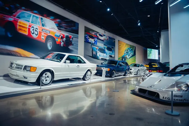 Rangée de Mercedes-Benz dans la galerie, en tête une 500 SEC AMG blanche, avec au premier plan une voiture de course Sauber-Mercedes argentée