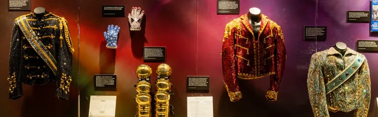 Vestes à paillettes de style militaire, gants ornés de strass et jambières dorées de Michael Jackson, présentés dans une vitrine