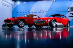 Deux coupés américains à carrosserie italienne rouge devant le titre mural « Transatlantic Lines: American Cars by Italian Masters »