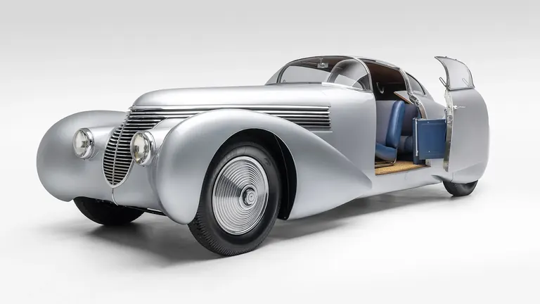 Coupé profilé Dubonnet Xenia argenté des années 1930, portière ouverte, sur fond blanc de studio