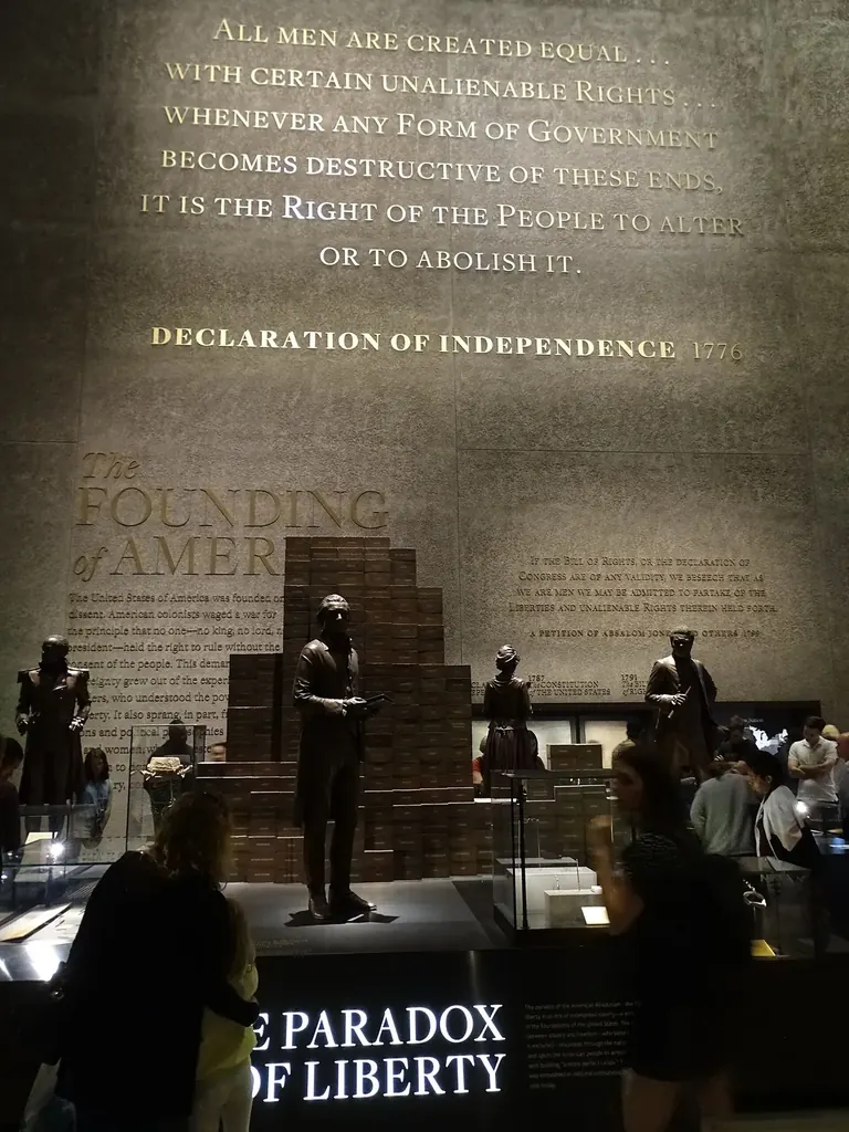 The Paradox of Liberty display in the Slavery and Freedom gallery, with a statue of Thomas Jefferson standing before a wall of bricks naming the people he enslaved