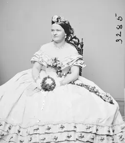Black-and-white Mathew Brady studio portrait of a woman in a dress holding flowers