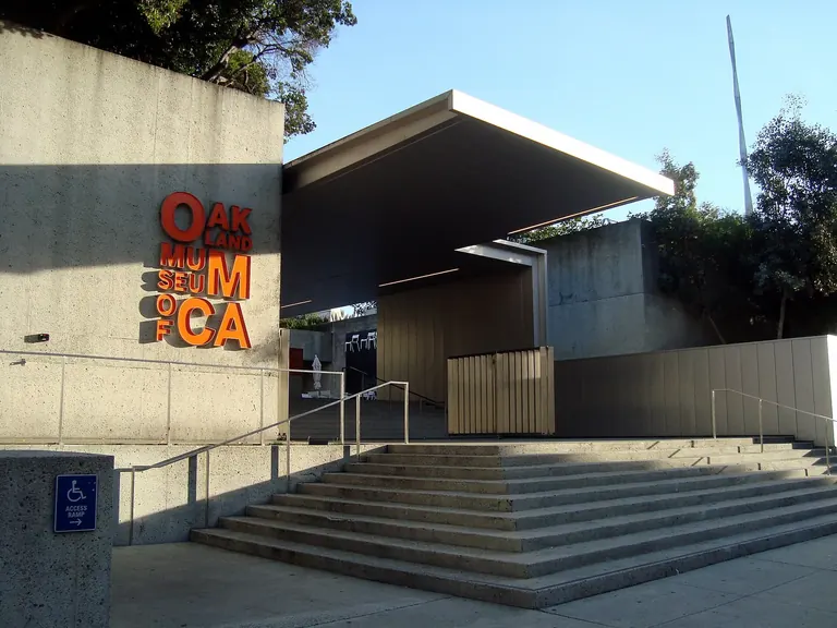 Marches d’entrée en béton et auvent en porte-à-faux de l’Oakland Museum of California, avec les lettres orange OMCA