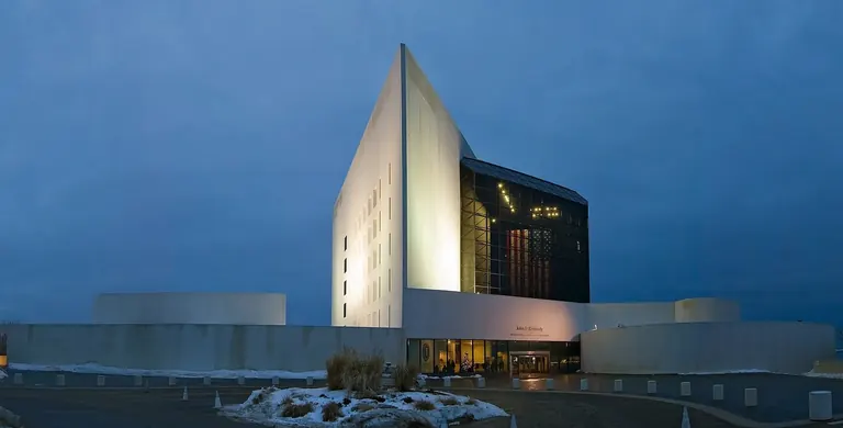 The white concrete tower and glass pavilion of the John F. Kennedy Presidential Library and Museum, designed by I. M. Pei, seen from across the water at Columbia Point, Boston