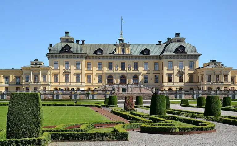 Façade baroque jaune du palais de Drottningholm, derrière les haies taillées de son jardin baroque à la française