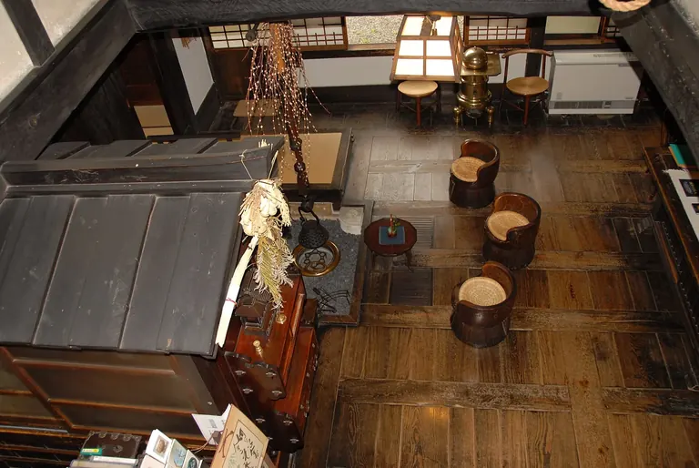 Pièce principale au plancher de bois de la maison de Kawai Kanjiro, à Kyoto, avec ses chaises, son foyer et son crochet à bouilloire suspendu