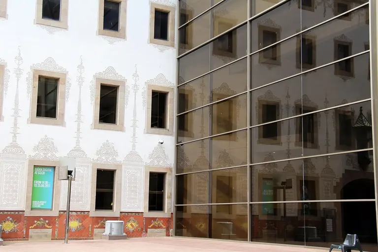 The CCCB courtyard, where the glass curtain wall reflects the sgraffito façade of the old Casa de Caritat