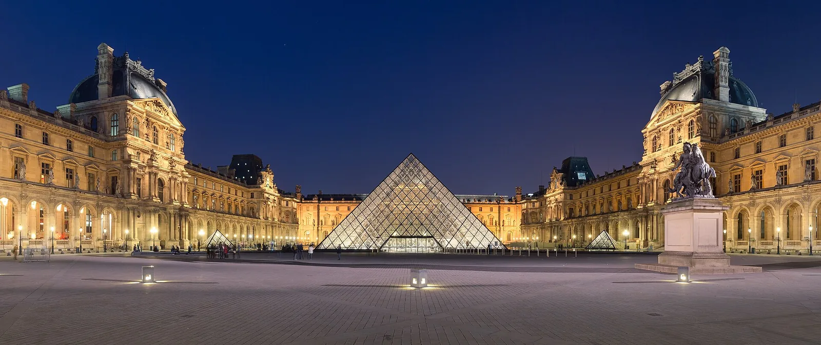 The Louvre's glass pyramid illuminated at night in the Napoleon Courtyard