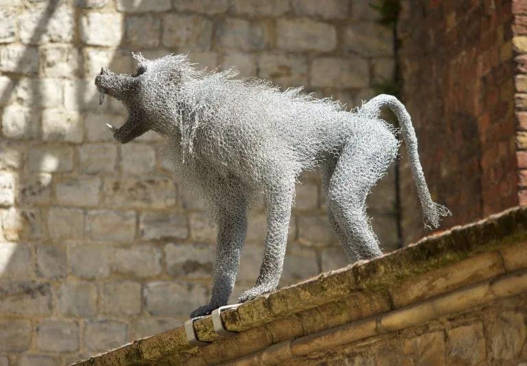 Wire sculpture of a baboon perched on a wall, part of the Royal Beasts exhibition at the Tower of London