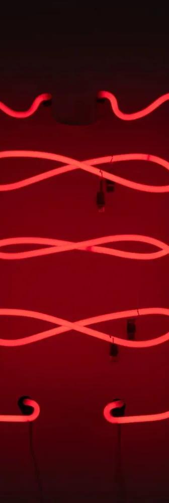 A glowing red neon light sculpture forms looping geometric curves against a dark background