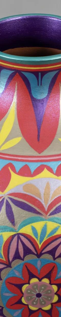 A round ceramic vase with a short neck decorated with intricate geometric and floral patterns painted in red, pink, blue, yellow, and purple.