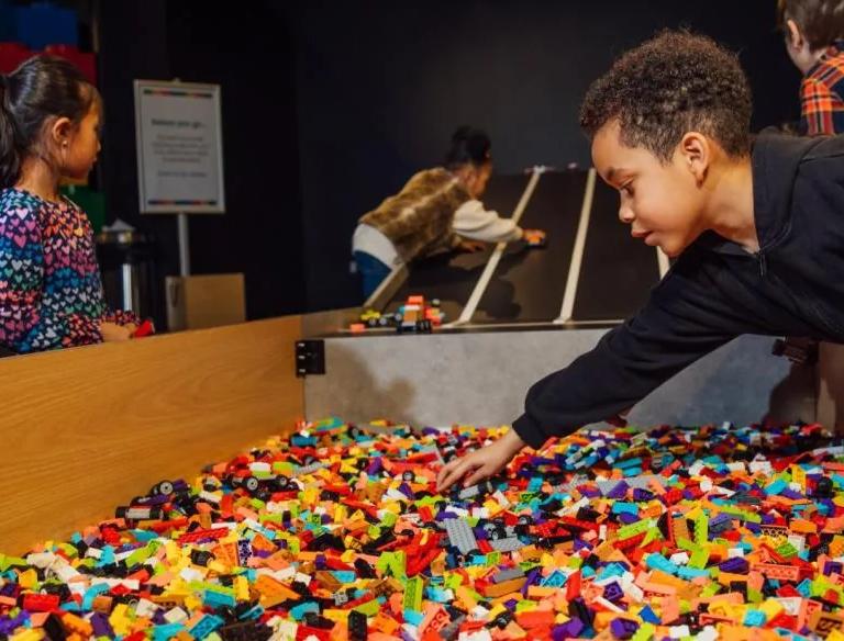 Children building on a ramp of LEGO bricks in the play space