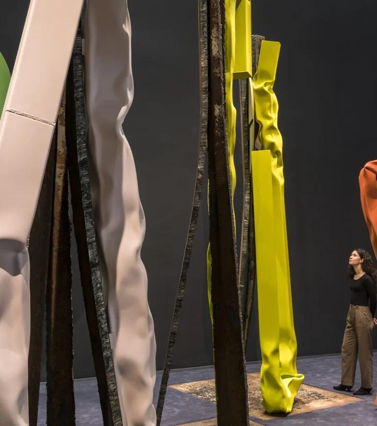 Brightly colored steel sculptures by Carol Bove in the Guggenheim's gallery, with a visitor looking up at the forms