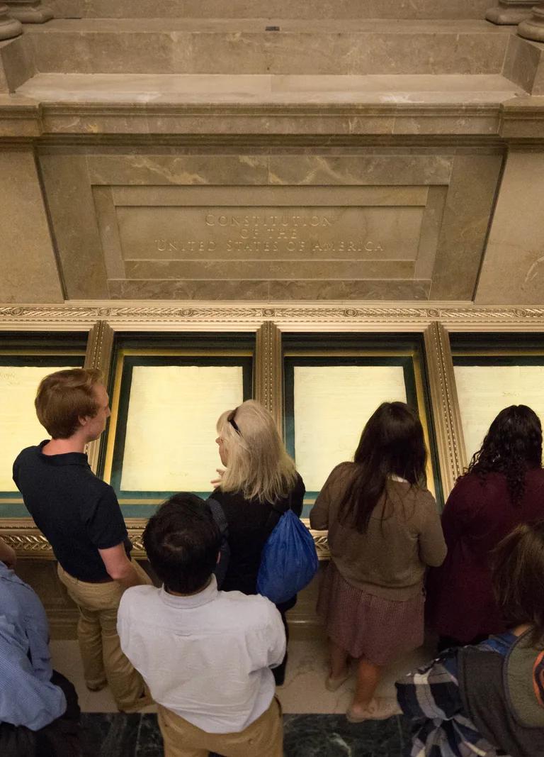 Visitors gathered around the encased original US Constitution in the National Archives Rotunda
