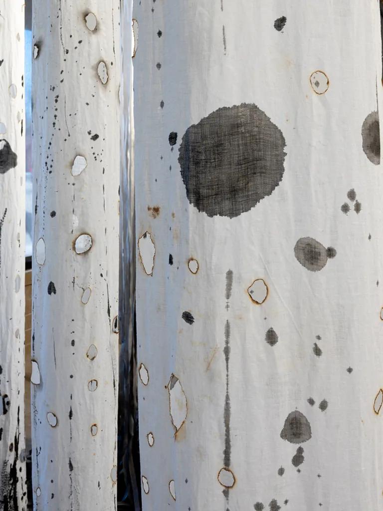 Katherine Steichen Rosing, Harbingers - tattered white linen columns charred with flame, suspended as a ghost forest