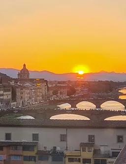 Florence skyline at dusk with Ponte Vecchio lit over the Arno River, seen from the Vasari Corridor route
