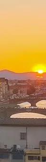 Florence skyline at dusk with Ponte Vecchio lit over the Arno River, seen from the Vasari Corridor route