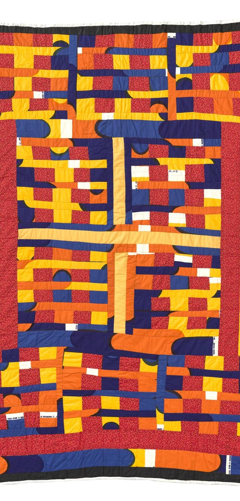 A vibrant, hand-quilted cotton textile features a combination of blue, orange, yellow, and red patchwork.