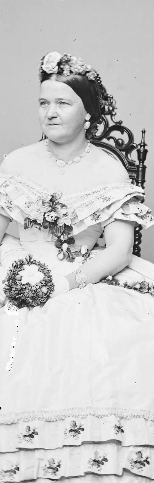 Black-and-white Mathew Brady studio portrait of a woman in a dress holding flowers