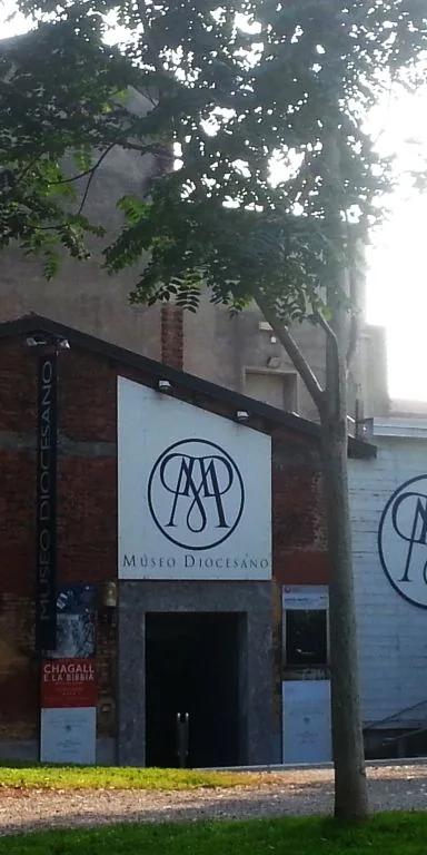 Entrance of the Museo Diocesano in Milan, a brick building with the museum's MD monogram, in the Sant'Eustorgio cloisters park