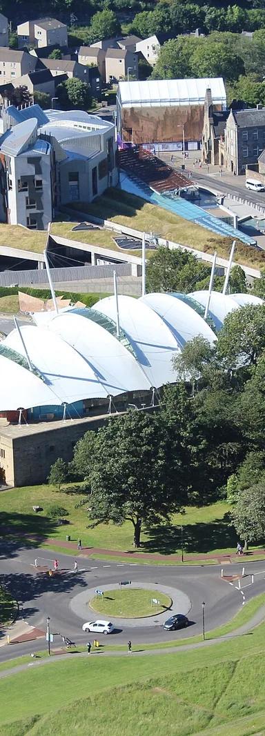 Dynamic Earth's white tented roof beside the Scottish Parliament, seen from Salisbury Crags