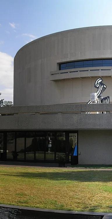 The cylindrical concrete exterior of the Hirshhorn Museum, raised on four piers, on the National Mall in Washington, DC