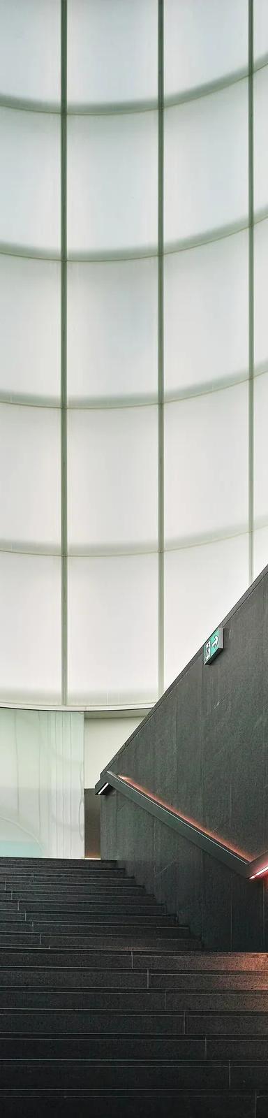 Stairway rising into the glowing glass Agorà of MUDEC, designed by David Chipperfield