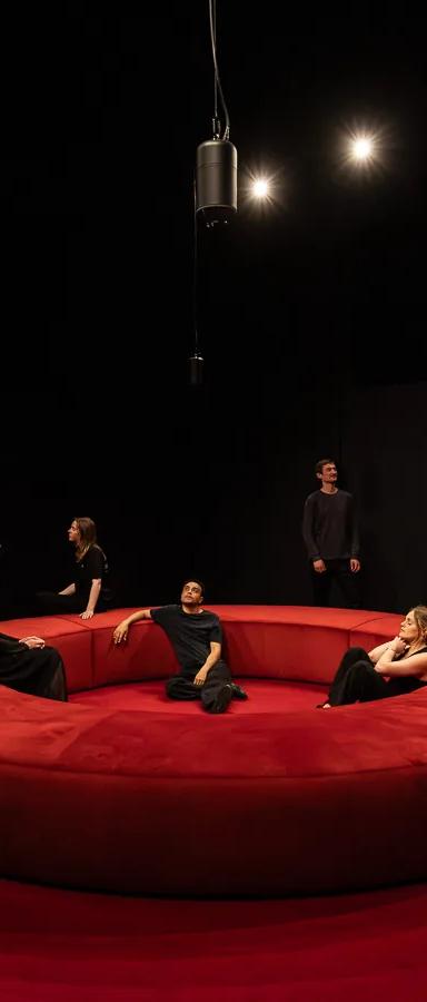 Visitors seated on a red circular bench in the darkened 4DSOUND spatial audio room at Nxt Museum, Amsterdam