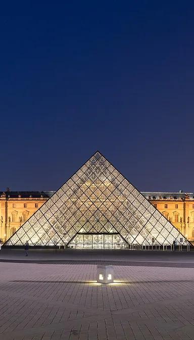The Louvre's glass pyramid illuminated at night in the Napoleon Courtyard